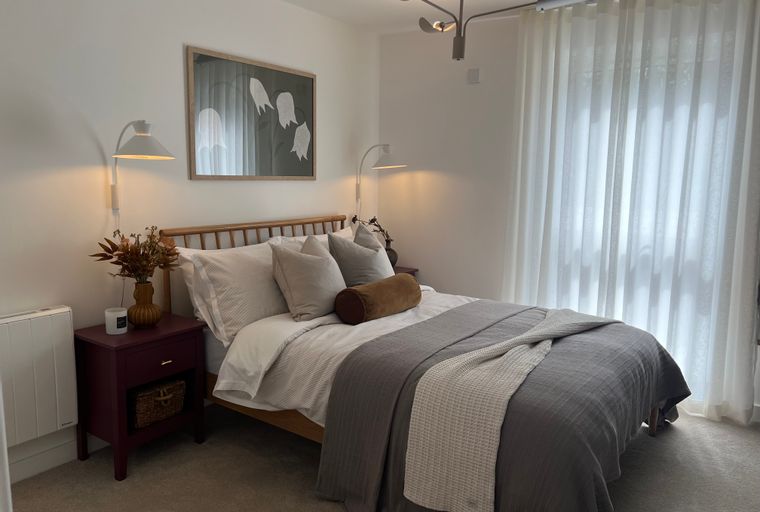 A bedroom with a bed, nightstand, and wall lamps.