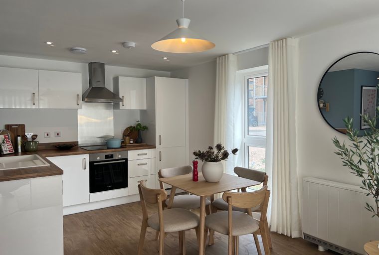 A kitchen and dining area with white cabinets, a dining table, and chairs.