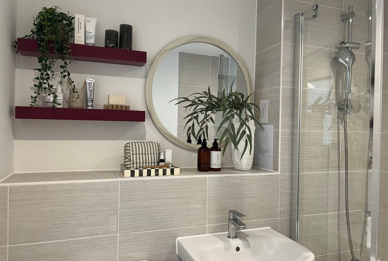A bathroom vanity with shelves, a mirror, a sink, and a shower.