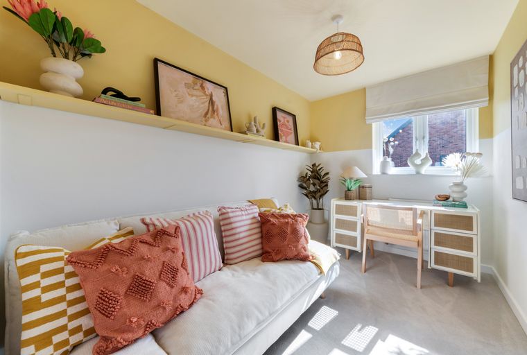 A living room with a sofa, desk, and window.