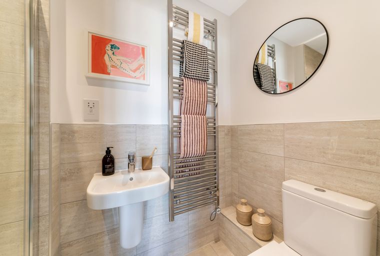 A bathroom with a sink, a toilet, a towel warmer, and a mirror.
