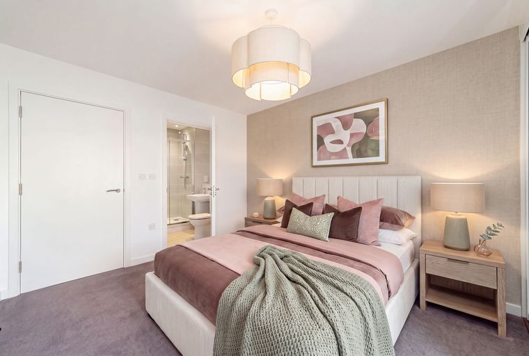 A bedroom with a bed, pillows, a blanket, and a doorway to a bathroom.