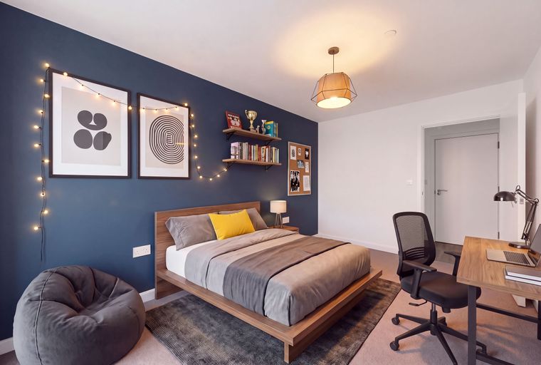 A bedroom with a bed, desk, chair, and beanbag.