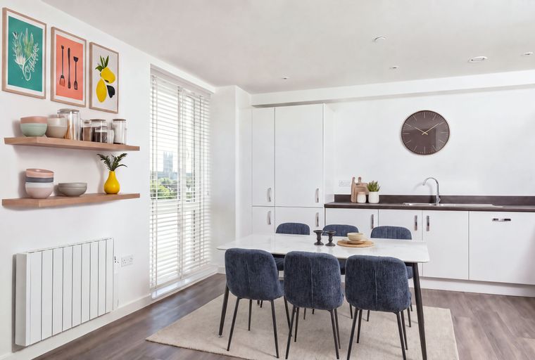 A dining area with a table, chairs, and a kitchen with cabinets and a sink.