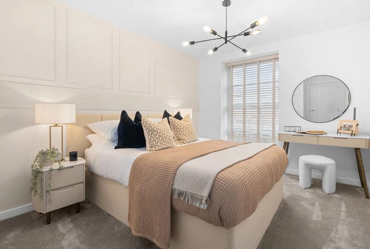 A bedroom with a bed, nightstand, vanity, and a chandelier.