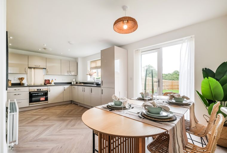 A dining area and kitchen with a table set for four and modern cabinetry.
