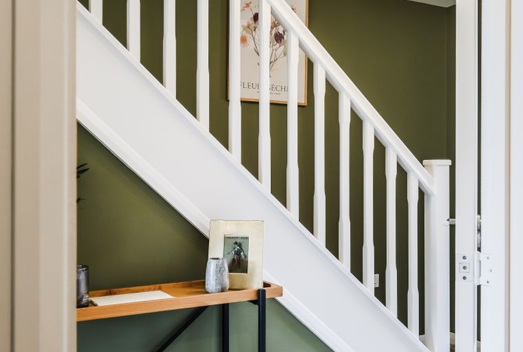 A staircase with white balusters and green walls.