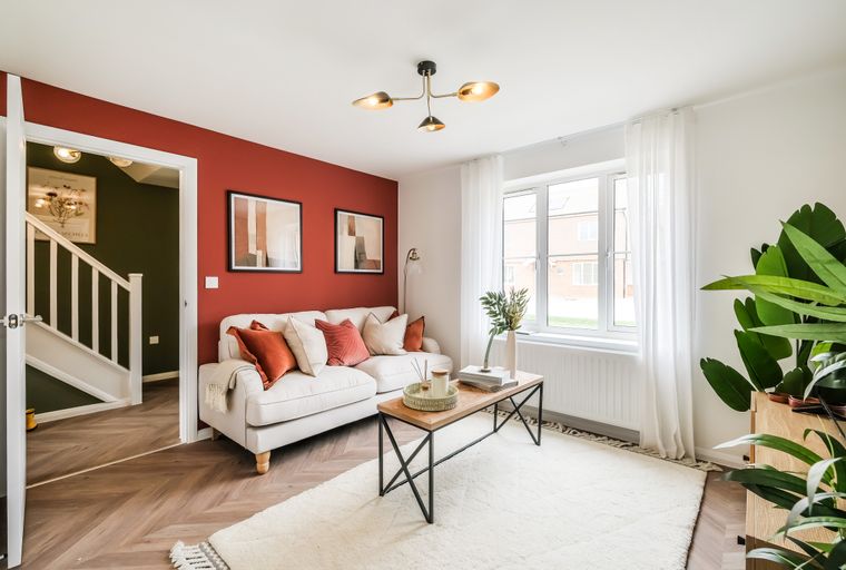 A living room with a sofa, coffee table, and artwork on a red wall.