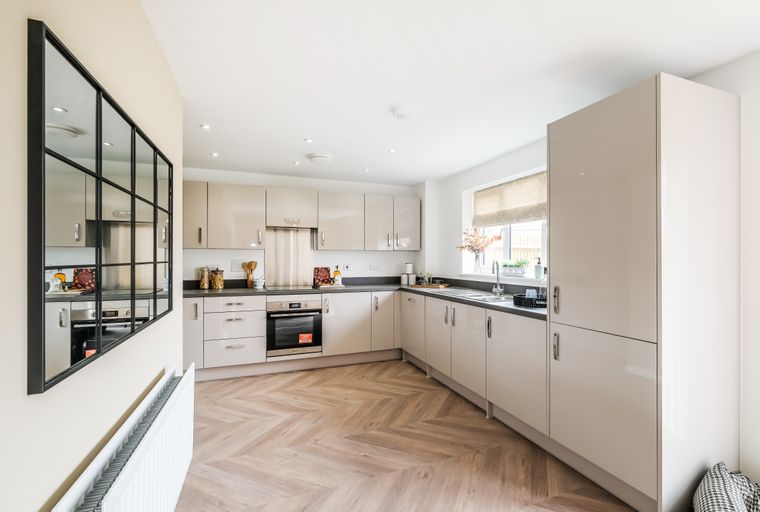 A modern kitchen with sleek cabinets, a dark countertop, and a herringbone floor.