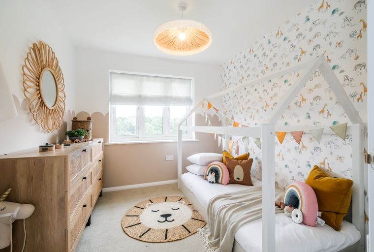 A child's bedroom with a house-shaped bed, animal wallpaper, and a wooden dresser.