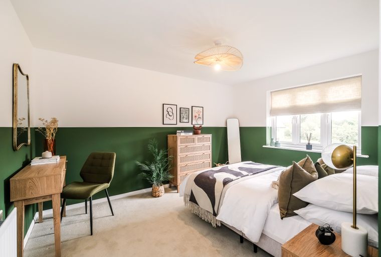 A bedroom with a bed, desk, chair, and dresser.