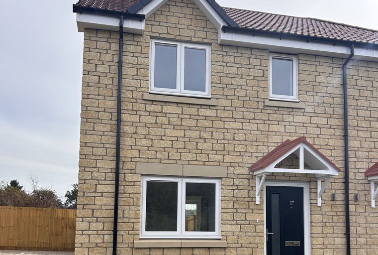 A new build house with a stone facade and a dark blue front door.