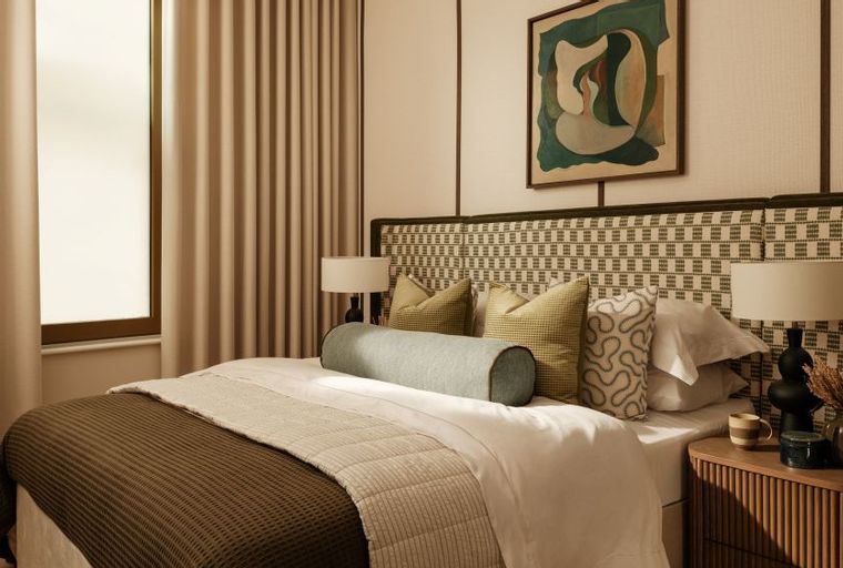 A bedroom with a bed, pillows, lamps, and a painting above the headboard.