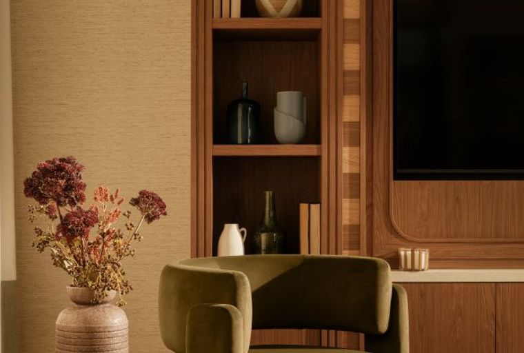 A living room with a bookshelf, an armchair, and a vase of flowers.