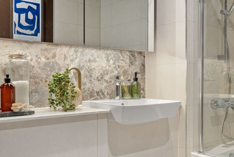 A bathroom with a sink, a mirror, and a shower.