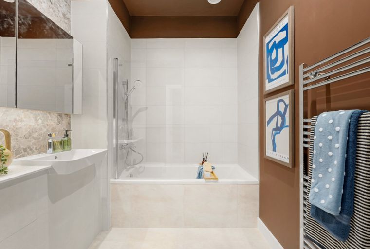A bathroom with a bathtub, sink, and towels on a heated rack.