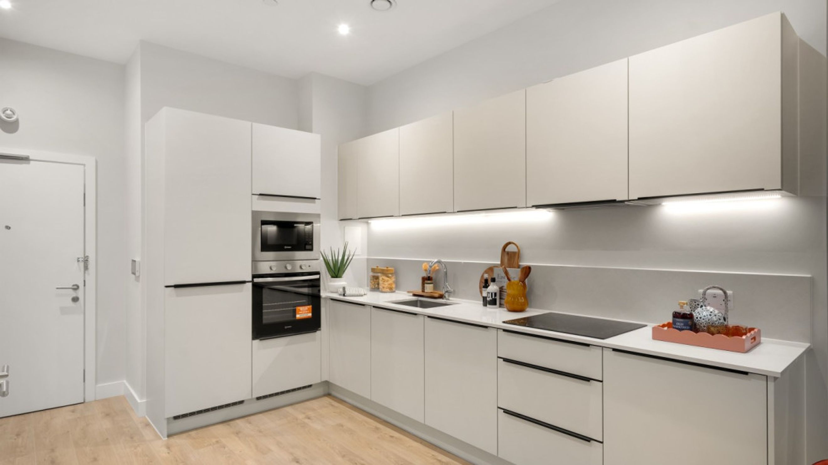 A modern kitchen with white cabinets, an oven, and a sink.