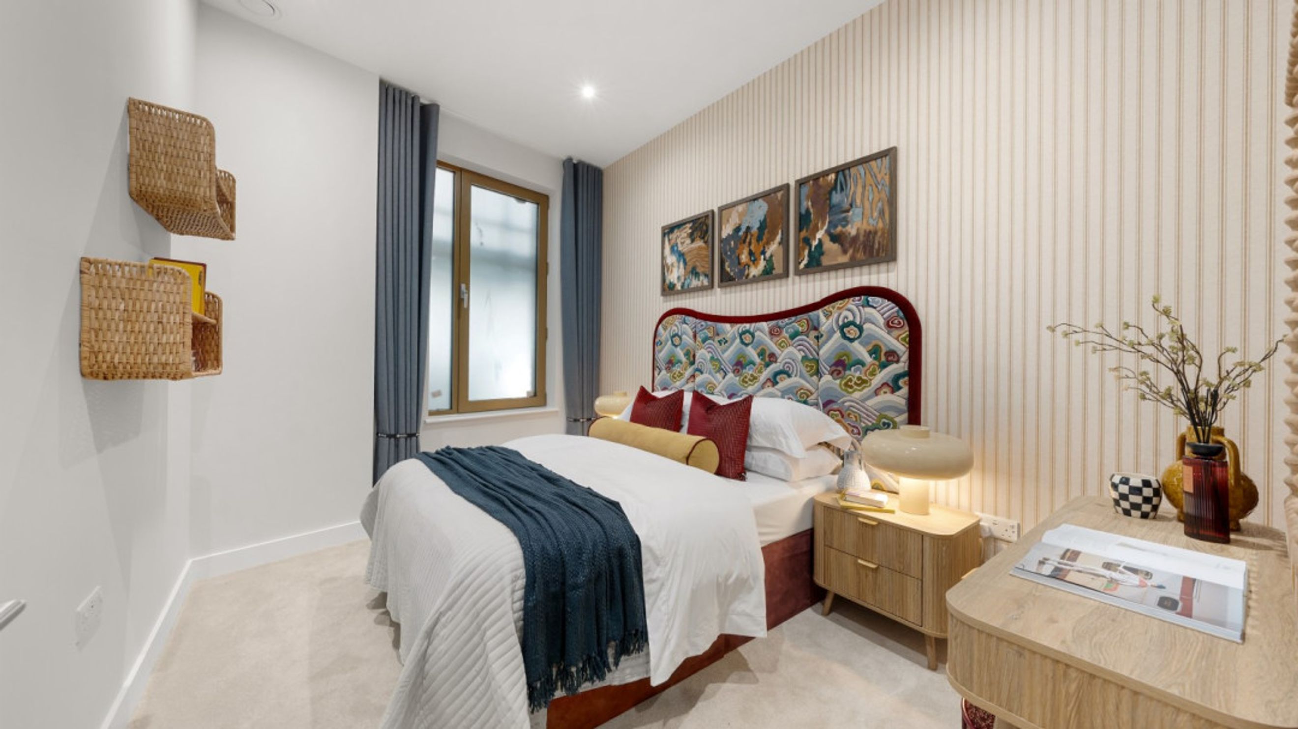 A bedroom with a bed, pillows, a throw blanket, and a bedside lamp.
