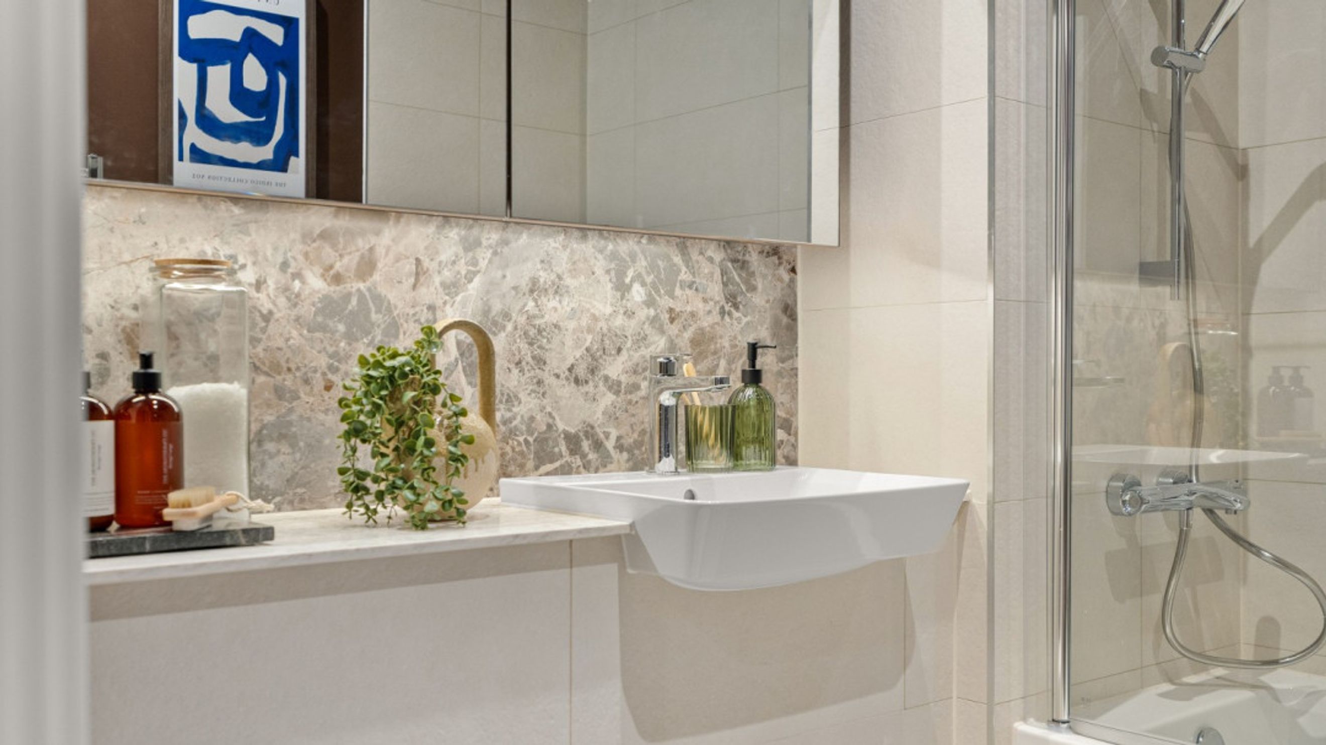 A bathroom with a sink, a mirror, and a shower.