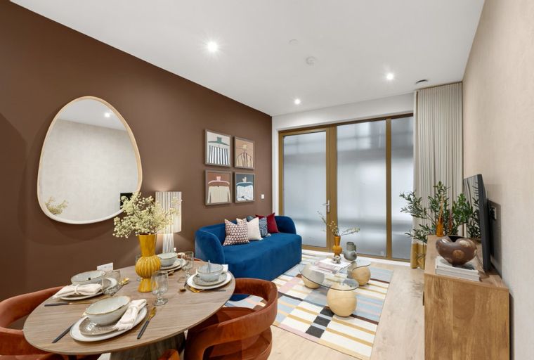 A dining area and living room with a blue sofa, dining table, and a television.