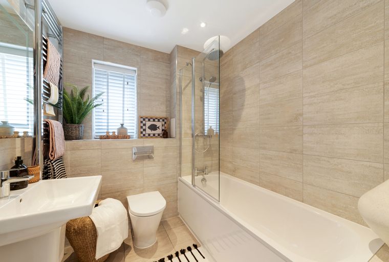 A bathroom with a bathtub, shower, toilet, sink, and tiled walls.