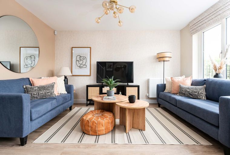 A living room with two blue sofas, coffee tables, and a television.