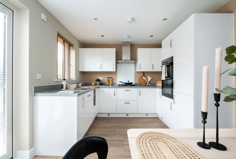 A modern U-shaped kitchen with white cabinets, grey countertops, and integrated appliances.