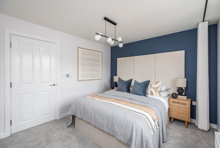 A bedroom with a bed, nightstand, and a door.