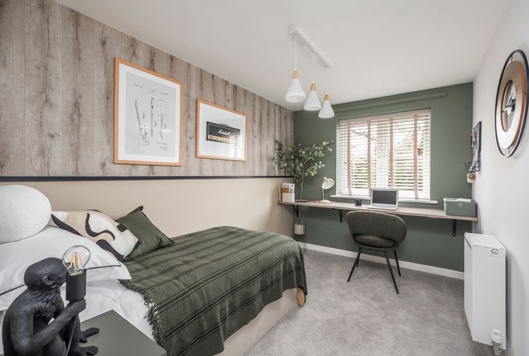 A bedroom with a bed, desk, chair, and wall art.