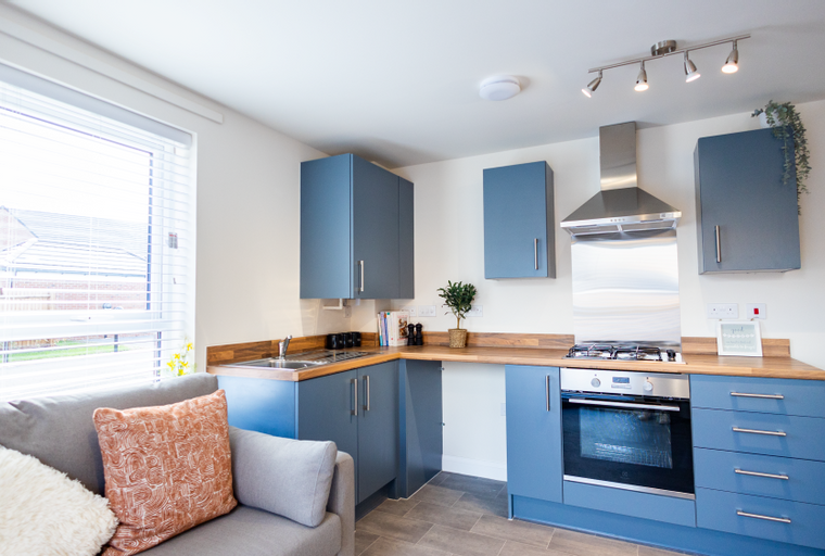 A modern kitchen with blue cabinets, wooden countertops, and a stainless steel oven and range hood.