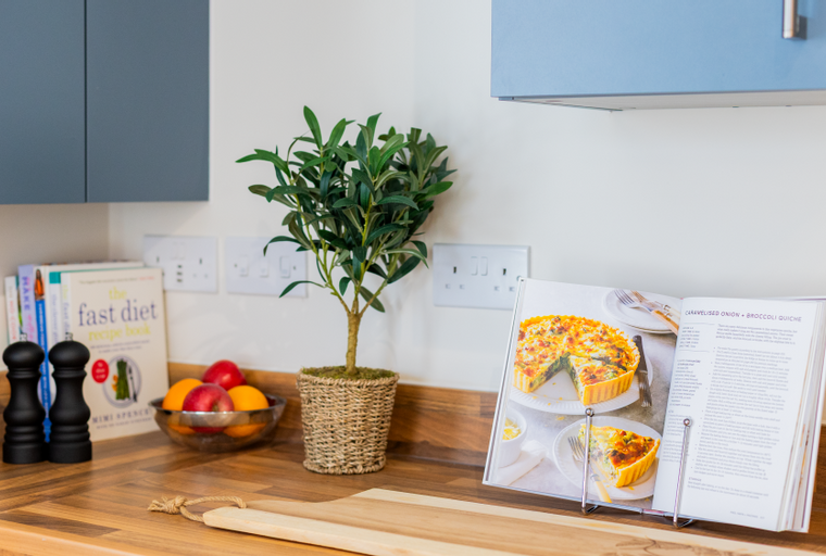 A kitchen counter with a cookbook, fruit bowl, and salt and pepper shakers.