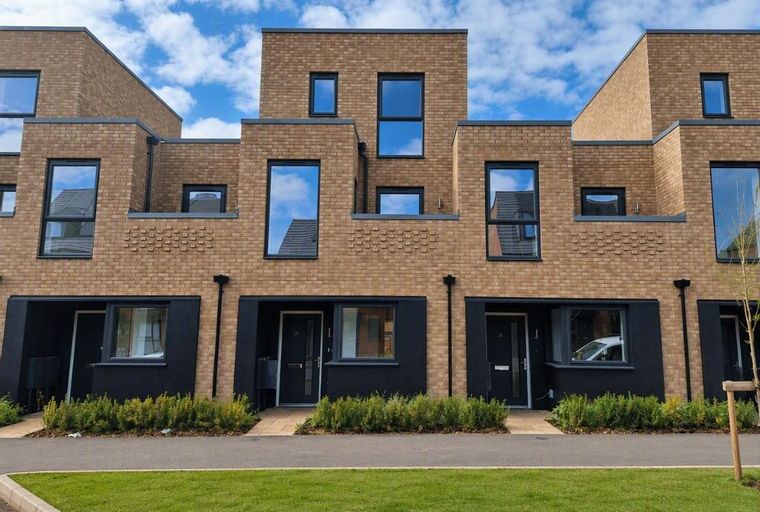A row of modern brick townhouses with dark-framed windows and black entranceways.