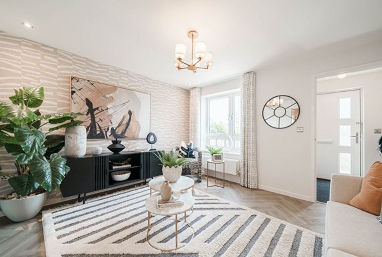 A living room with a media console, artwork, rug, and a large plant.