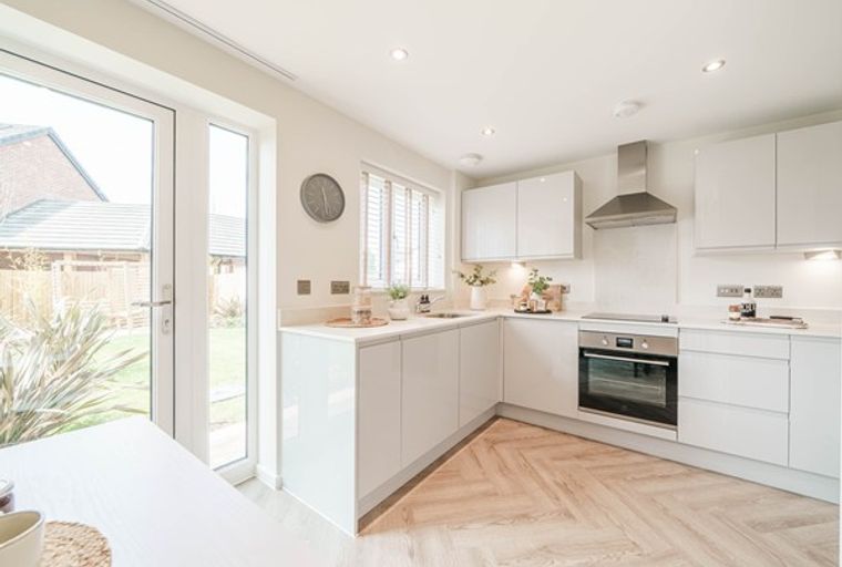 A modern kitchen with white cabinets, a built-in oven, and a range hood.