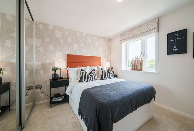 A bedroom with a bed, bedside table, and a large window.