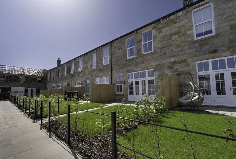 A row of stone buildings with gardens and a hanging chair.