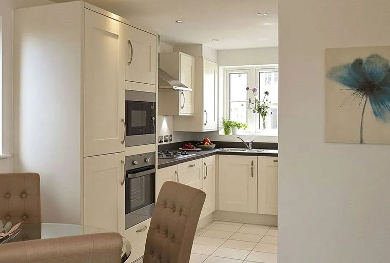 A modern kitchen with cream cabinets, integrated appliances, and a window above the sink.