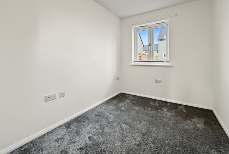 A room with a window, carpet, and electrical outlets.