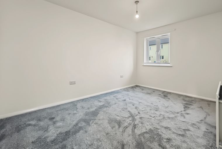 A room with grey carpet, white walls, and a window.