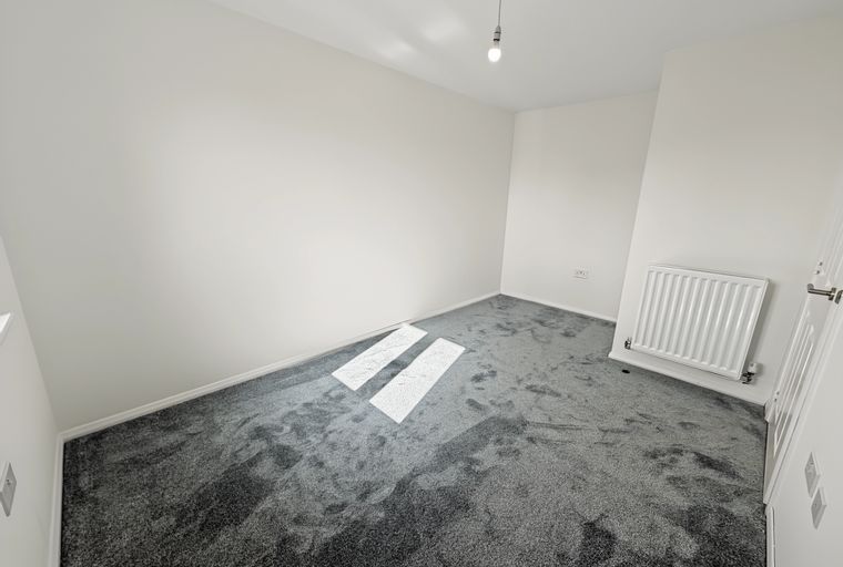 A room with grey carpet and white walls.
