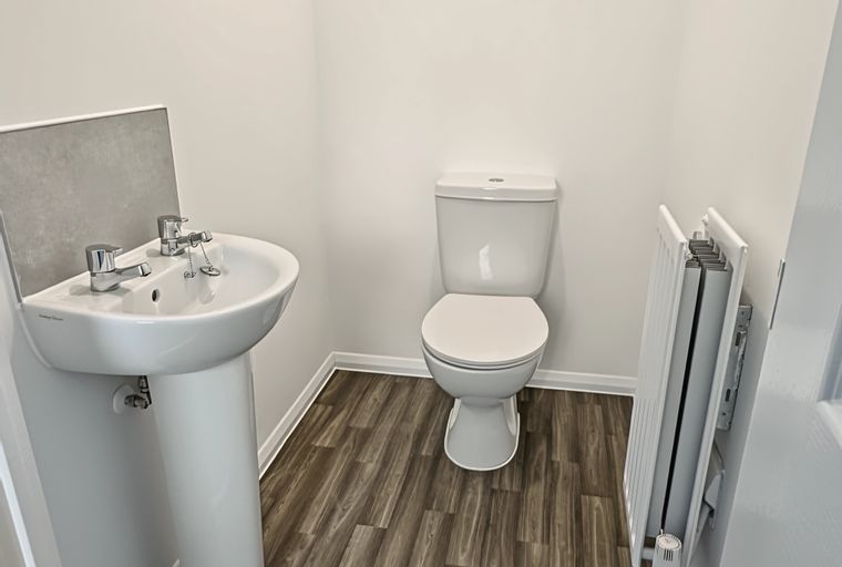 A bathroom with a sink, toilet, and radiator.