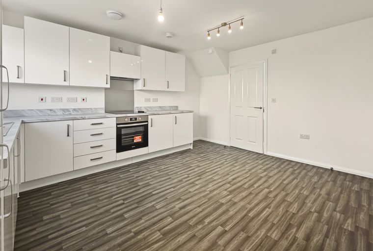 A modern kitchen with white cabinets, a marble countertop, and a built-in oven.
