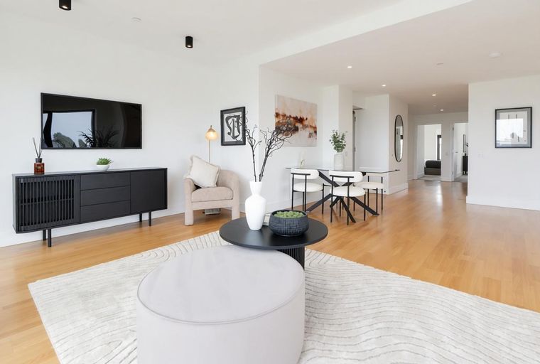 A living room and dining area with a TV, media console, armchair, dining table, and chairs.