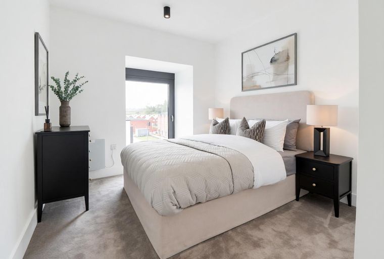 A bedroom with a bed, bedside tables, and a dresser.