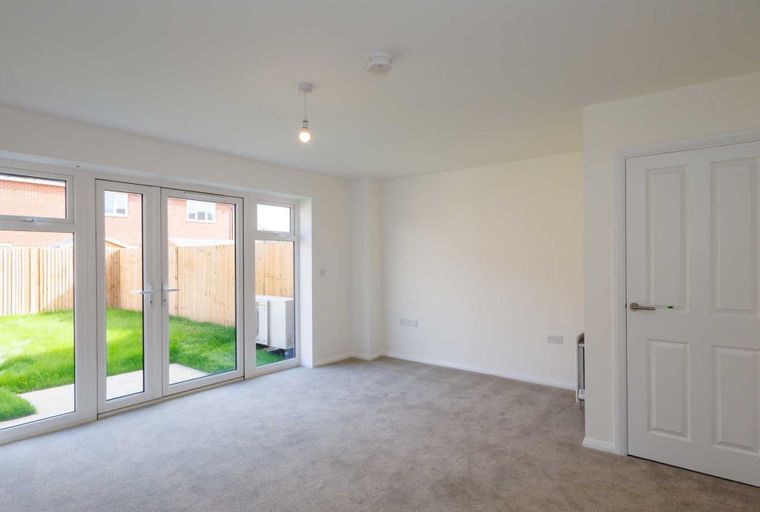 A living room with double doors leading to a garden and an interior door.