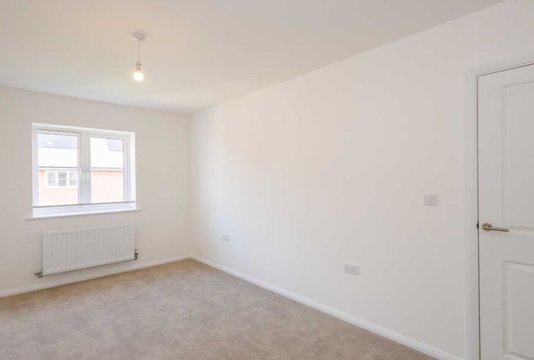 A bedroom with a window and a radiator.