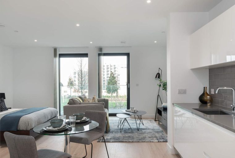 A studio apartment with a bed, sofa, dining table, and kitchen.