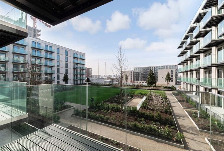 A view of modern apartment buildings with balconies overlooking a communal garden.