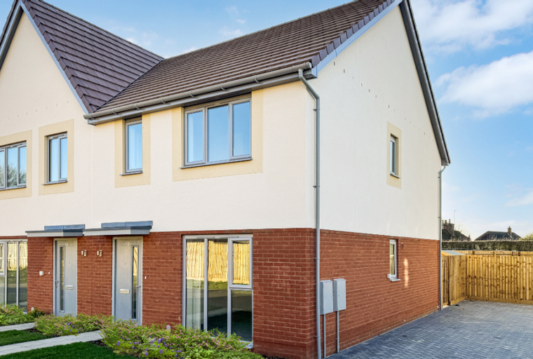A modern semi-detached house with red brick and cream render, featuring multiple windows and a paved driveway.