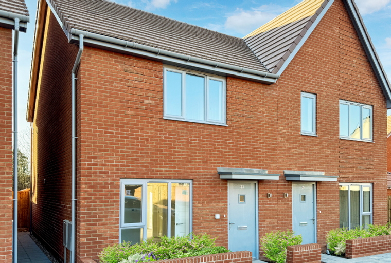 A row of modern red brick houses with grey doors and windows under a blue sky.